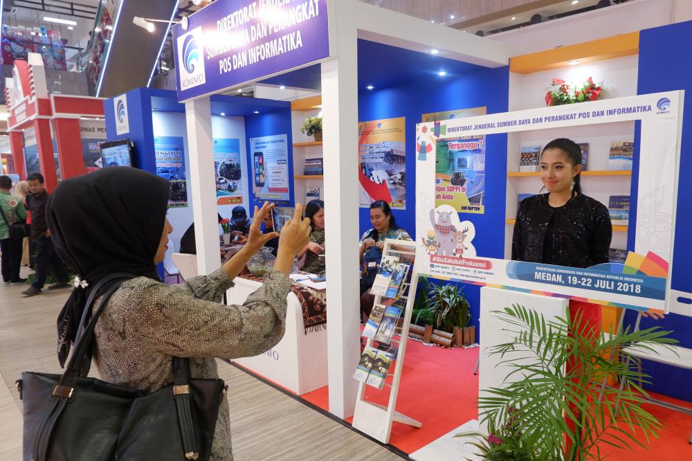 Pengunjung memanfaatkan frame booth Ditjen SDPPI untuk berfoto ria pada pameran Medan ITT Expo 2018 (19/7). Pameran digunakan oleh Ditejn SDPPI untuk mensosailisasikan tertib penggunaan frekeunsi Radio dan standardisasi alat dan perangkat teleokunikasi.